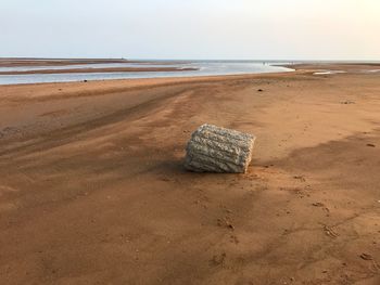 Scenic view of sand on beach against sky