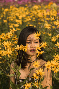 Young woman amidst yellow flowers in field