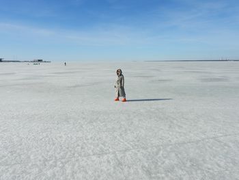 Rear view of woman walking on snow covered field