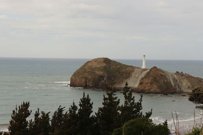 View of castle point light house from a distance. there a trees in the foreground.