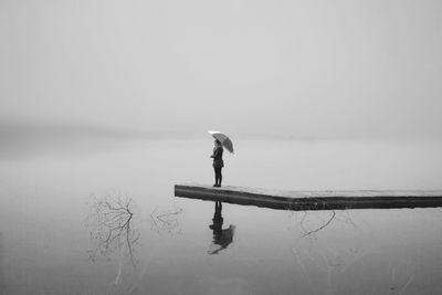 Man standing on lake against sky