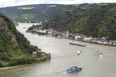 Tourist ships and barges sailing on the river rhine in western germany, visible buildings and hills.