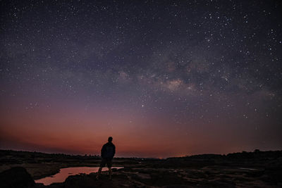 Man standing on field against sky at night
