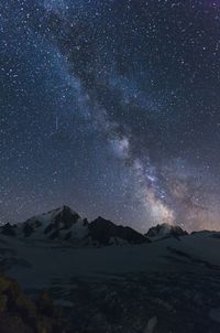 Scenic view of snowcapped mountains against sky at night