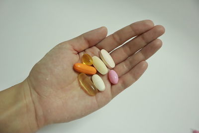 Close-up of hand holding ice cream over white background