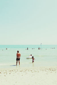 People on beach against clear sky