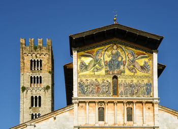 Top of the basilica of saint frediano with a huge golden mosaic and the stone bell tower, lucca, tus
