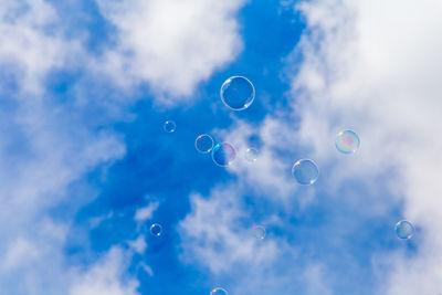 Low angle view of bubbles against rainbow in sky