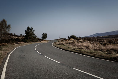 Empty road along landscape against clear sky