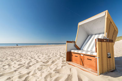 Hooded beach chair at beach against clear blue sky