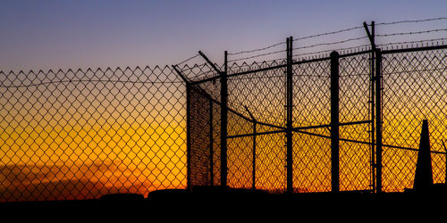 Silhouette fence against clear sky during sunset