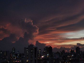 Panoramic view of illuminated buildings against dramatic sky