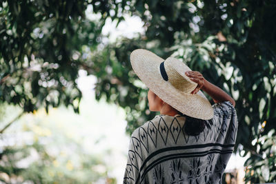 Rear view of woman wearing hat while standing against trees