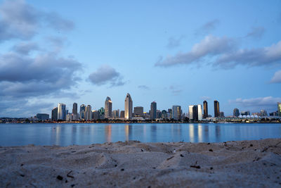 Sea by modern buildings against sky in city