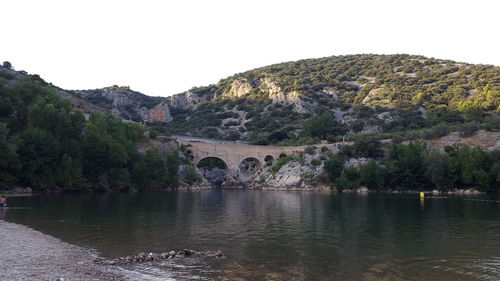 Scenic view of river by mountains against clear sky