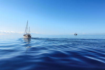 Sailboat in sea against clear blue sky