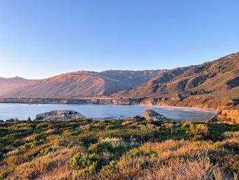 Scenic view of land and mountains against clear sky