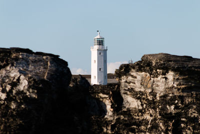 Low angle view of lighthouse by buildings against clear sky