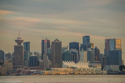 Modern buildings in city against sky during sunset