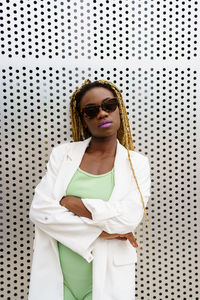 Young woman looking away while standing against white wall