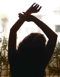 Rear view of silhouette woman with arms raised