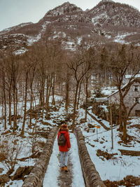 Rear view of woman with backpack standing on footpath in forest during winter