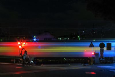 Man cycling against blurred motion of train at night