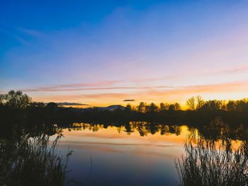Scenic view of pond against sky during sunset