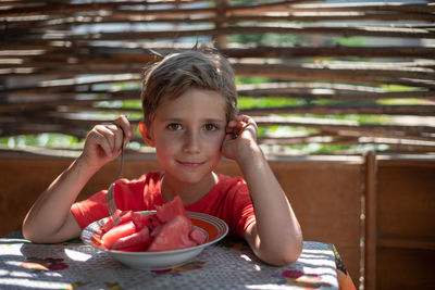 Portrait of boy having watermelon in plate at table