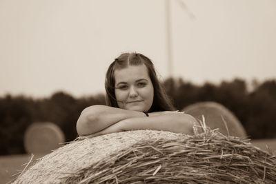 Portrait of smiling girl standing by haystack on field