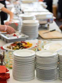 Cropped hands of person stacking plates on table in ceremony