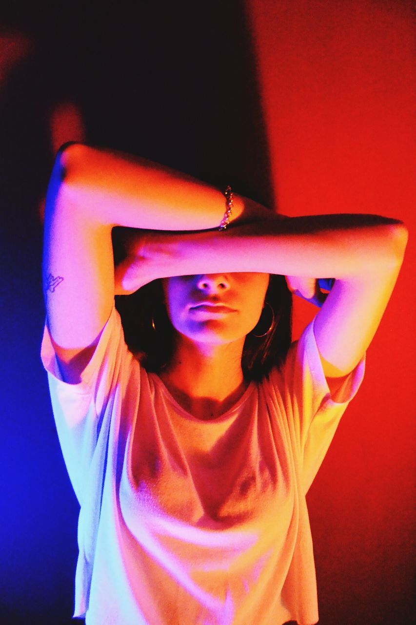 PORTRAIT OF BEAUTIFUL YOUNG WOMAN STANDING AGAINST WALL IN ROOM