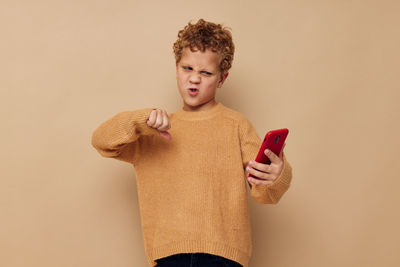 Portrait of young woman using mobile phone against yellow background