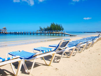 Chairs on beach against blue sky