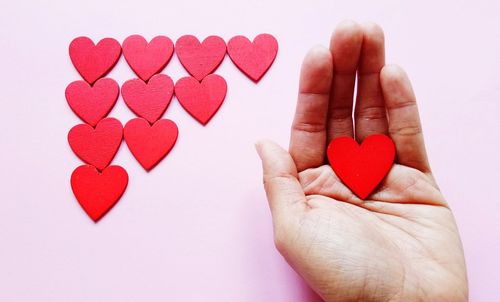 Close-up of hand holding heart shape over white background