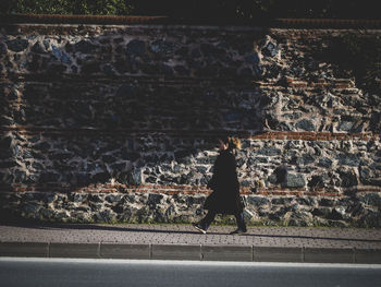 Rear view of woman walking against wall