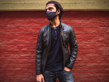 Portrait of young man standing against wall