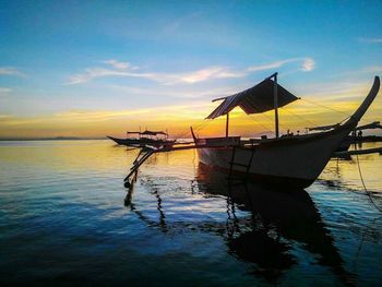 Boats in sea at sunset