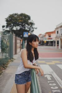 Young woman standing on road in city