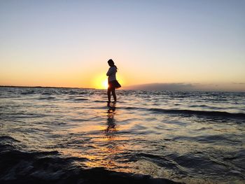 Woman wading in sea against clear sky