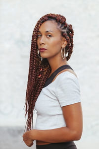 Portrait of young woman with braided hair against white background
