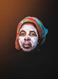 Close-up portrait of a man wearing mask against black background