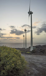 Windmills on beach against sky