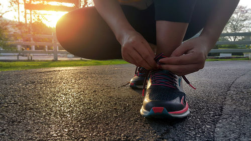 Low section of woman with umbrella on road