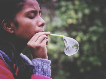 Close-up of woman blowing bubble at park