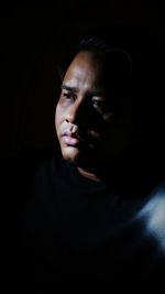 Close-up of thoughtful man against black background