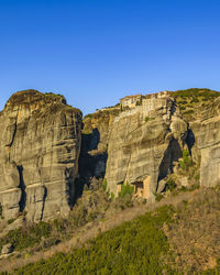 Rock formations on landscape against clear blue sky