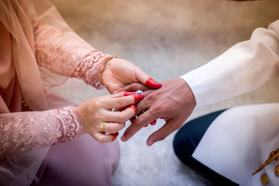 Midsection of bride putting wedding ring in groom finger