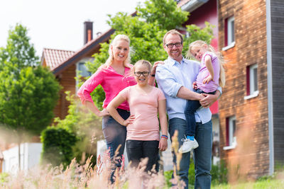Portrait of smiling family standing against house