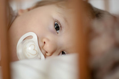 Close-up portrait of cute baby boy with pacifier in mouth